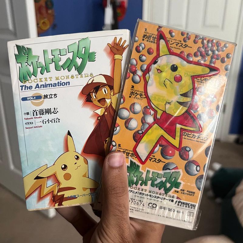 Kel's copy of Pokémon Master Mix, released in June 1997, and Pocket Monsters: The Animation Vol. 1, written by anime chief writer Takeshi Shudo and released in October 1997